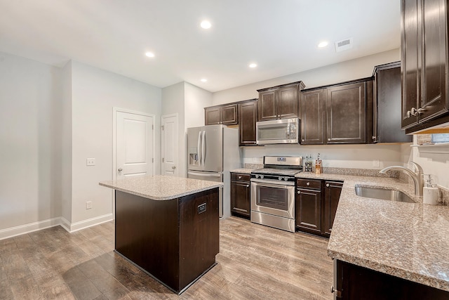 kitchen with dark brown cabinetry, appliances with stainless steel finishes, a sink, a center island, and visible vents