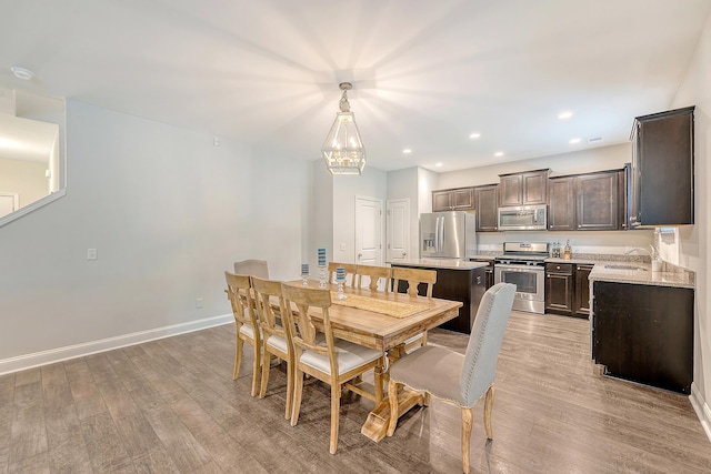 dining area with recessed lighting, baseboards, a notable chandelier, and light wood-style flooring