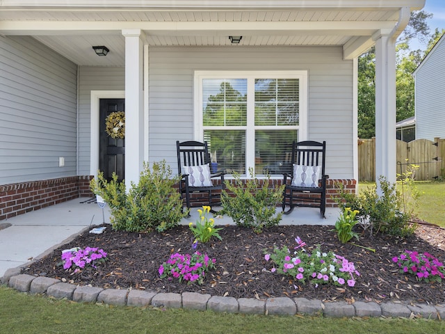 view of exterior entry with fence and a porch