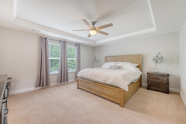 bedroom with visible vents, baseboards, light colored carpet, a tray ceiling, and a ceiling fan