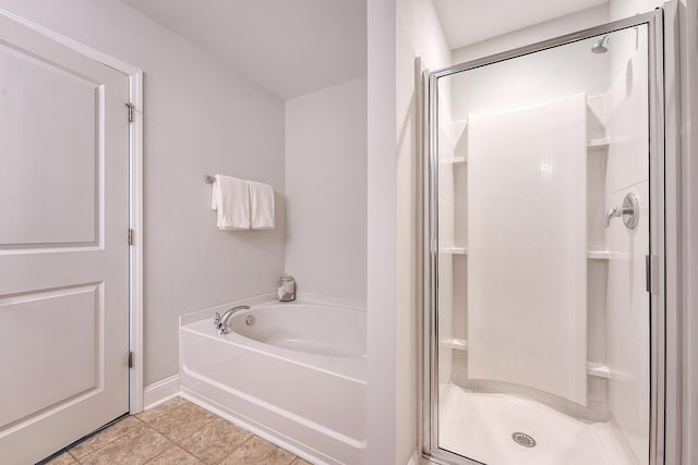 bathroom with baseboards, tile patterned floors, a bath, and a stall shower