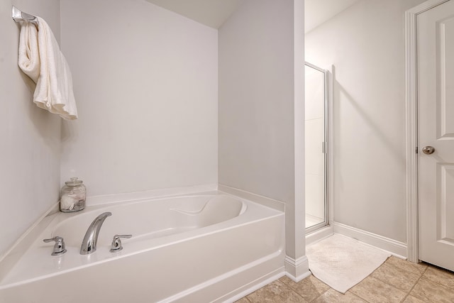 bathroom with baseboards, tile patterned flooring, a garden tub, and a stall shower