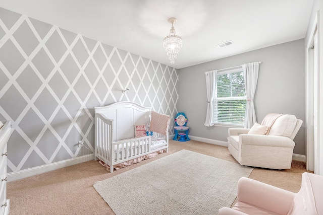 carpeted bedroom with visible vents, baseboards, a crib, and a chandelier