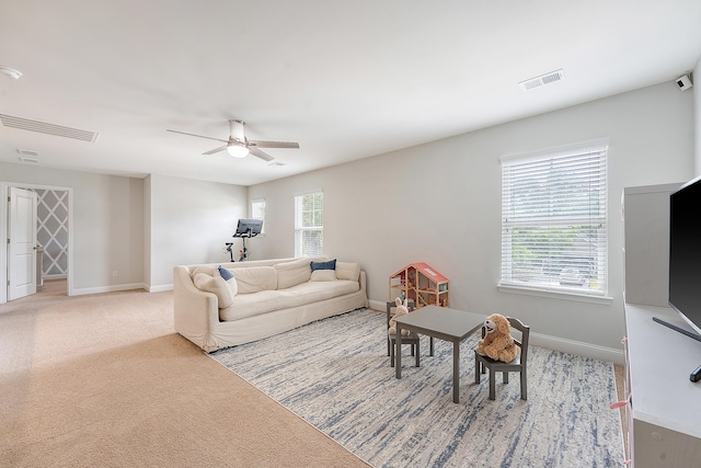 living area featuring baseboards, ceiling fan, light carpet, and visible vents