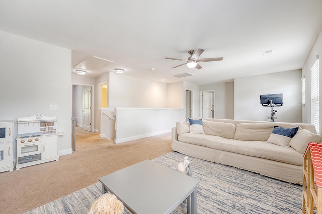 living room featuring a ceiling fan, visible vents, light carpet, and attic access