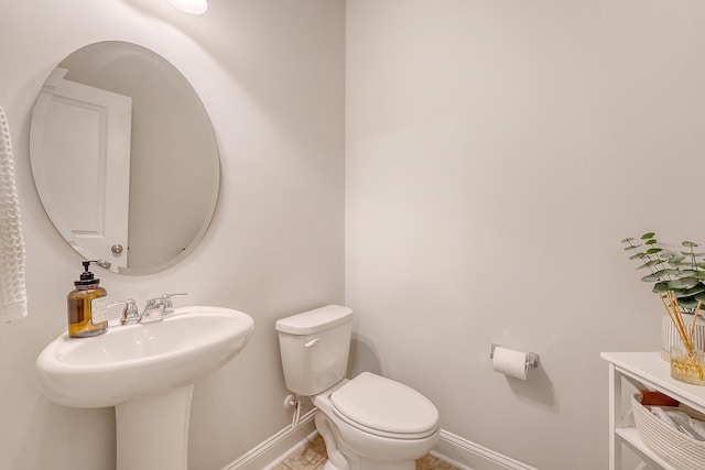 half bathroom with baseboards and toilet