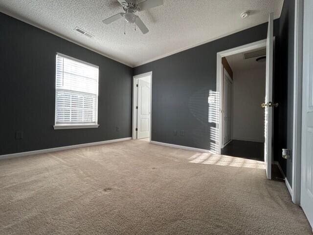 unfurnished bedroom featuring carpet, a textured ceiling, and ceiling fan