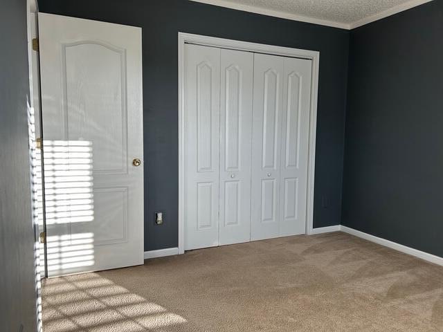 unfurnished bedroom featuring light carpet, a closet, and a textured ceiling