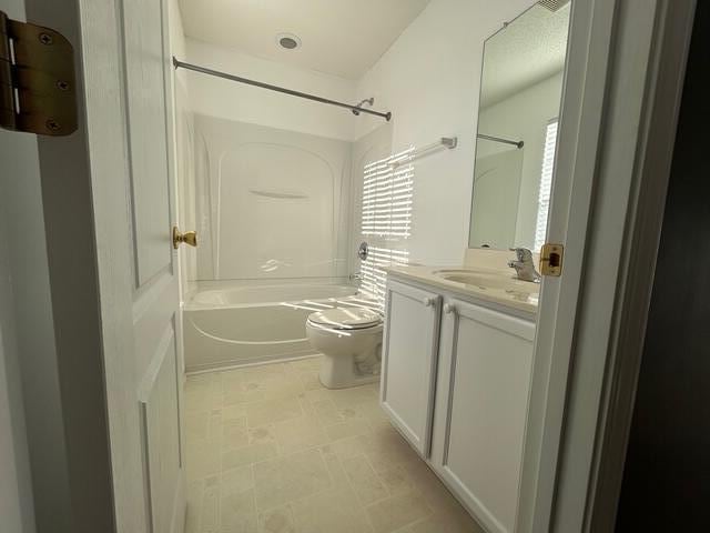 full bathroom featuring washtub / shower combination, vanity, and toilet