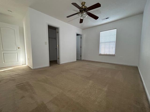 unfurnished bedroom featuring ceiling fan, a closet, carpet, and a spacious closet