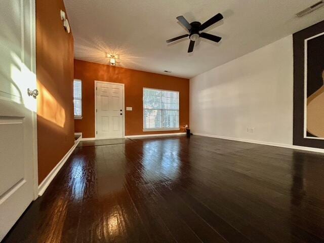 unfurnished living room featuring ceiling fan and dark wood-type flooring