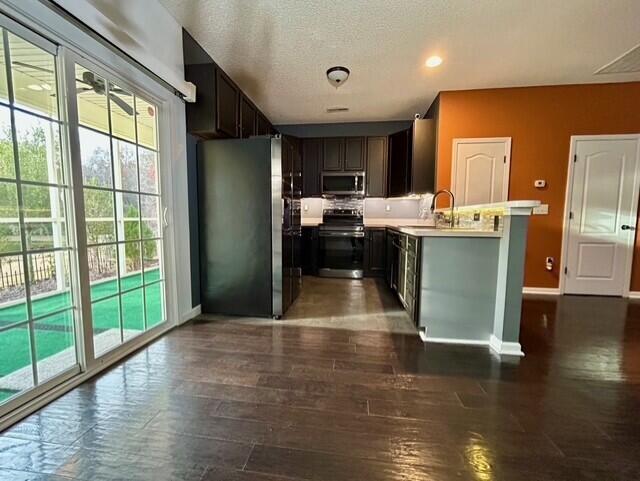 kitchen featuring appliances with stainless steel finishes, dark hardwood / wood-style flooring, dark brown cabinetry, a textured ceiling, and sink