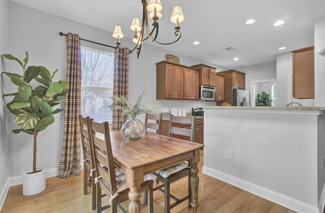 dining room with light hardwood / wood-style floors and an inviting chandelier