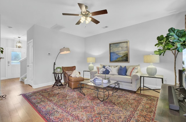 living room with ceiling fan with notable chandelier and hardwood / wood-style flooring