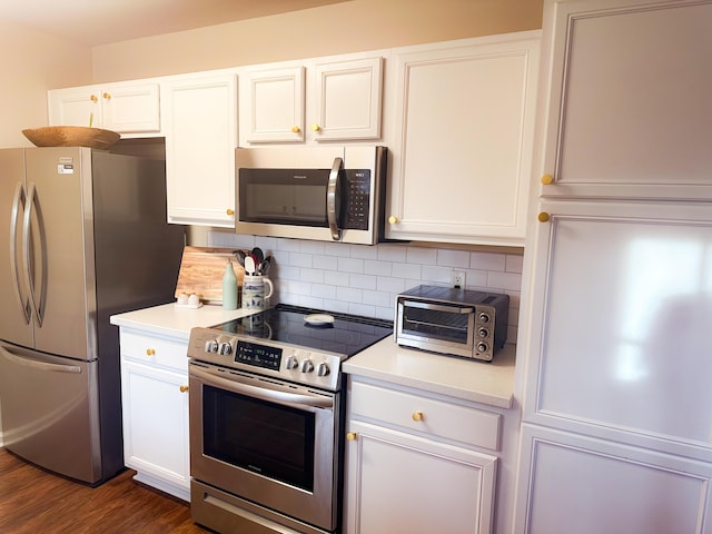 kitchen featuring backsplash, stainless steel appliances, dark wood-type flooring, and white cabinets