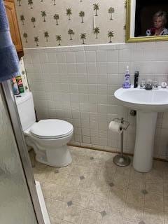 bathroom featuring tile floors, backsplash, toilet, and tile walls