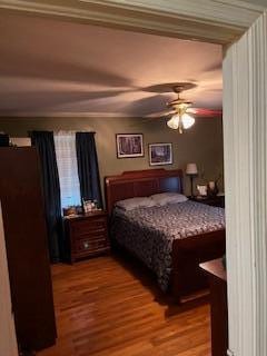 bedroom with ceiling fan, crown molding, and wood-type flooring