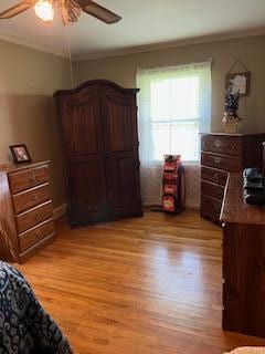 bedroom with ceiling fan, light hardwood / wood-style floors, and crown molding