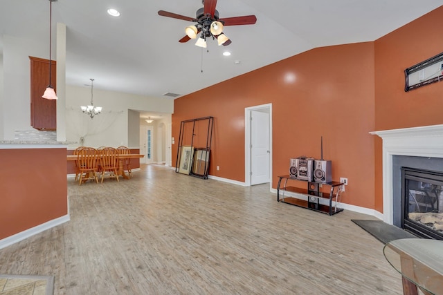 living room with ceiling fan with notable chandelier, light hardwood / wood-style floors, and lofted ceiling