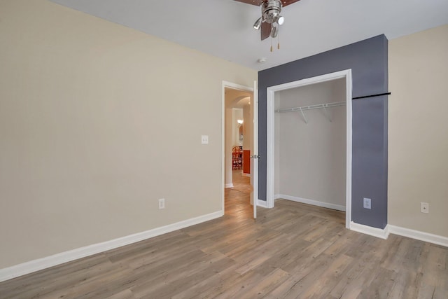 unfurnished bedroom featuring ceiling fan, light wood-type flooring, and a closet