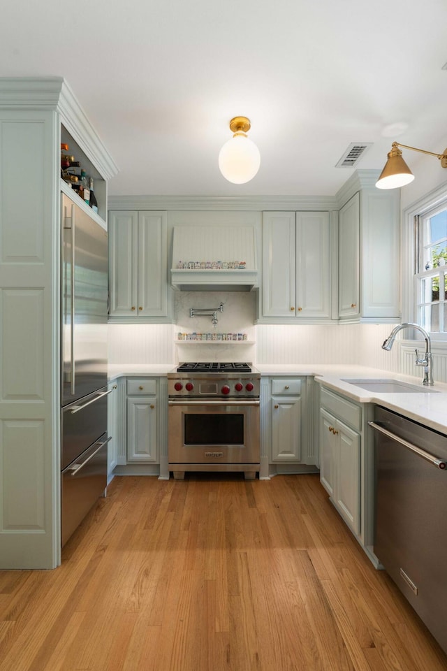 1661/2 Queen St, Charleston, SC 29401 - kitchen with high quality appliances, custom exhaust hood, a sink, light wood-style floors, and light countertops