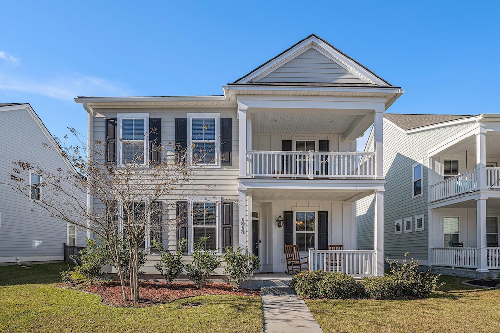 view of front of home with a porch, a balcony, and a front lawn