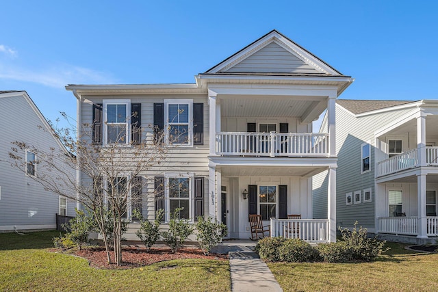 view of front of home with a porch, a balcony, and a front lawn