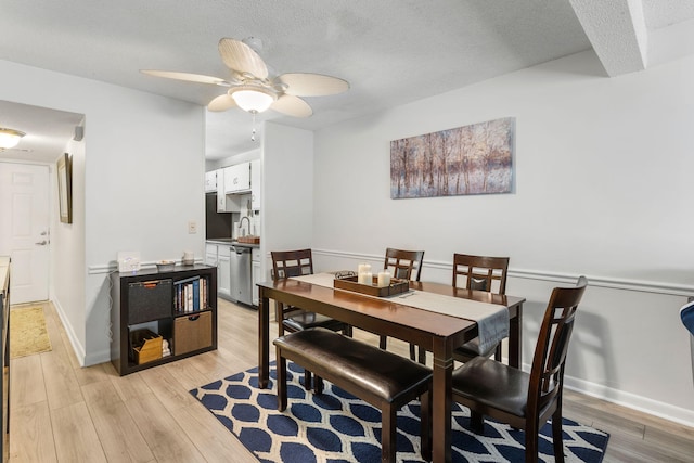 dining area with light hardwood / wood-style floors, sink, ceiling fan, and a textured ceiling