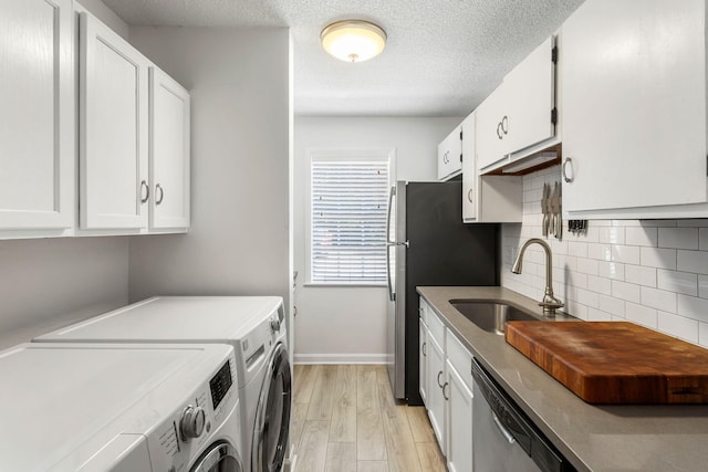 laundry room with a textured ceiling, washer and clothes dryer, light hardwood / wood-style floors, and sink