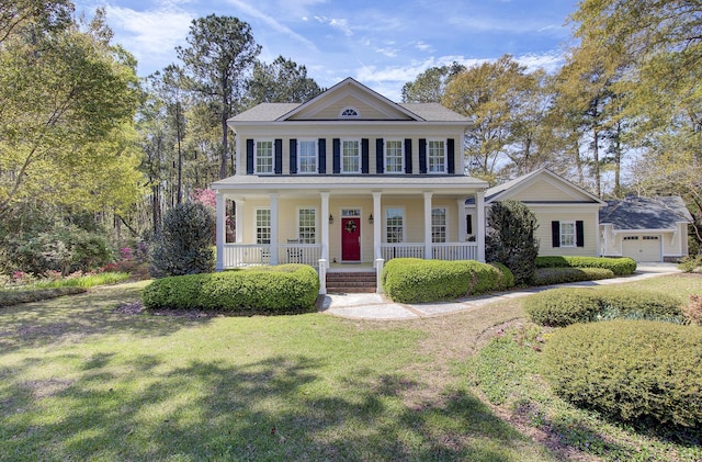 greek revival house featuring covered porch, a front yard, and a garage