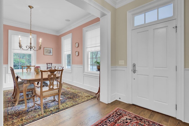 dining area featuring a chandelier, wood finished floors, wainscoting, and crown molding