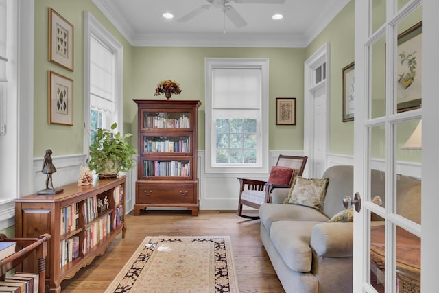 sitting room with a ceiling fan, ornamental molding, light wood-type flooring, wainscoting, and recessed lighting