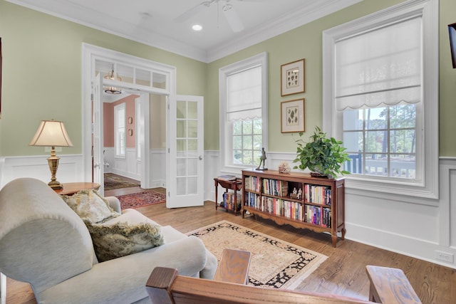 living area with ceiling fan, crown molding, a wainscoted wall, wood finished floors, and recessed lighting