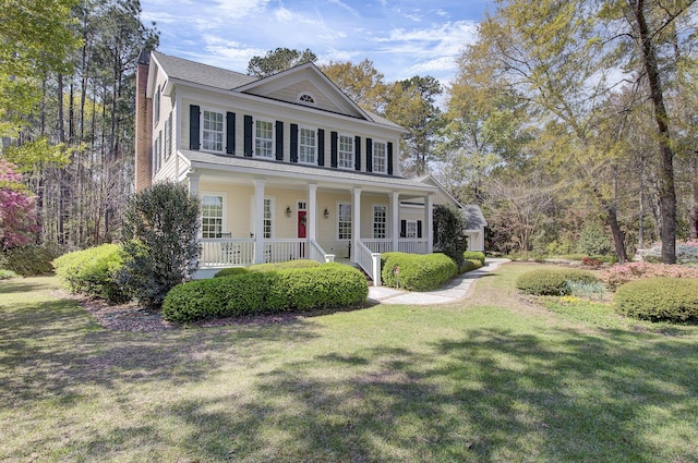 neoclassical / greek revival house featuring a front lawn and a porch