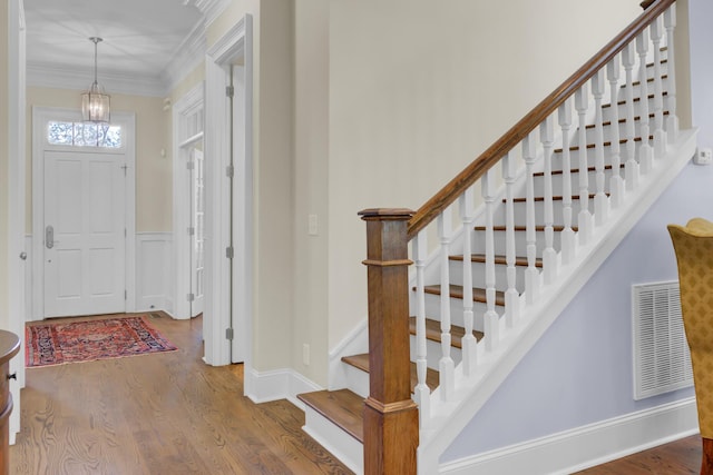entrance foyer featuring wood finished floors, stairs, a chandelier, crown molding, and baseboards