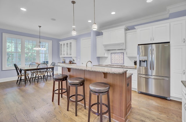 kitchen featuring stainless steel appliances, light stone counters, a breakfast bar area, white cabinetry, and ornamental molding