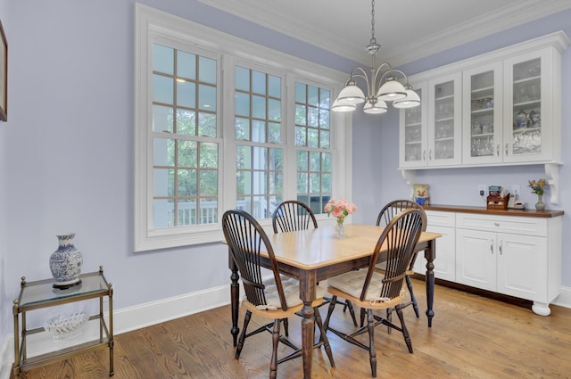 dining room with a chandelier, healthy amount of natural light, baseboards, crown molding, and light wood-type flooring