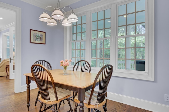 dining area featuring healthy amount of natural light, baseboards, crown molding, a chandelier, and wood finished floors