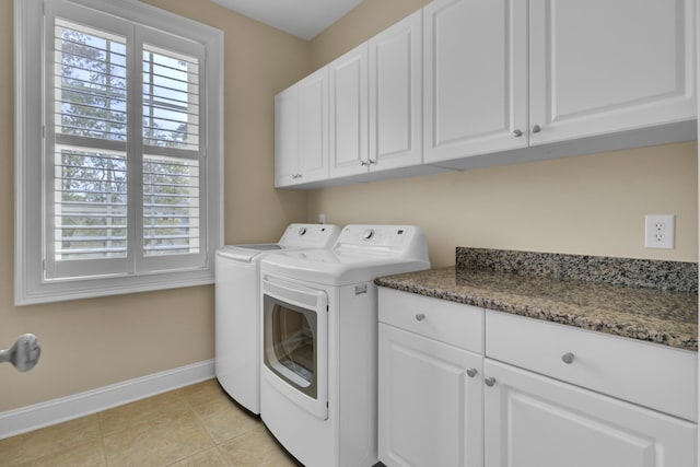 clothes washing area featuring baseboards, cabinet space, washer and dryer, and plenty of natural light