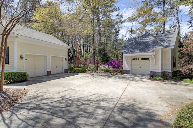 view of home's exterior featuring concrete driveway, roof with shingles, brick siding, and a garage