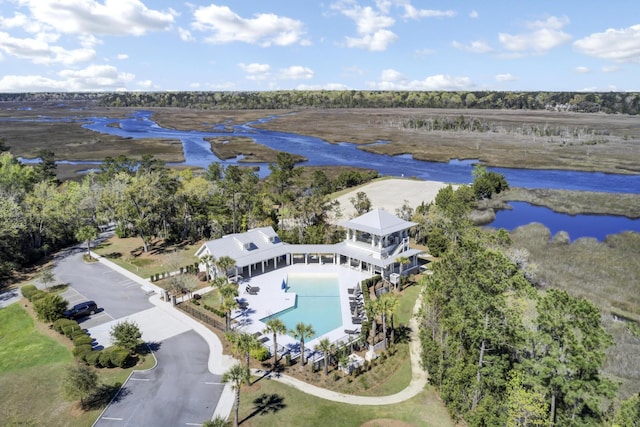 bird's eye view of a pool, a nearby body of water, and a tree filled landscape