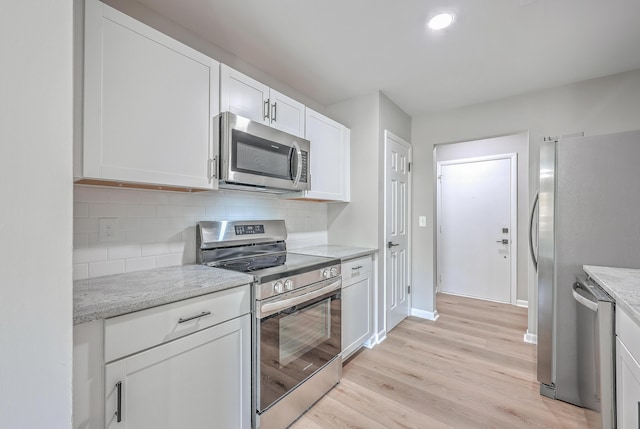 kitchen with white cabinets, stainless steel appliances, tasteful backsplash, light hardwood / wood-style floors, and light stone counters