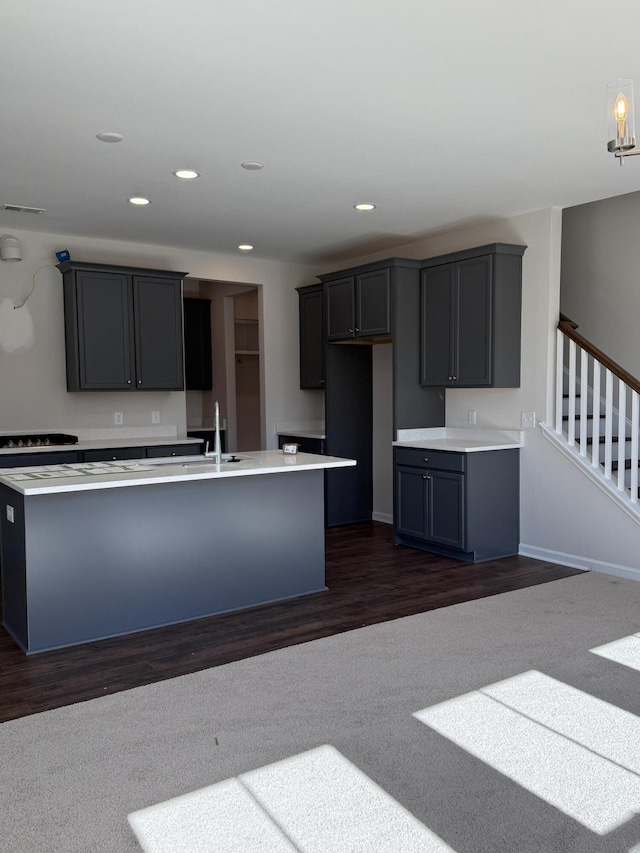 kitchen featuring light countertops, recessed lighting, a kitchen island with sink, and a sink