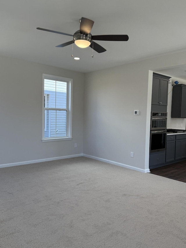 interior space with a ceiling fan, baseboards, and dark colored carpet