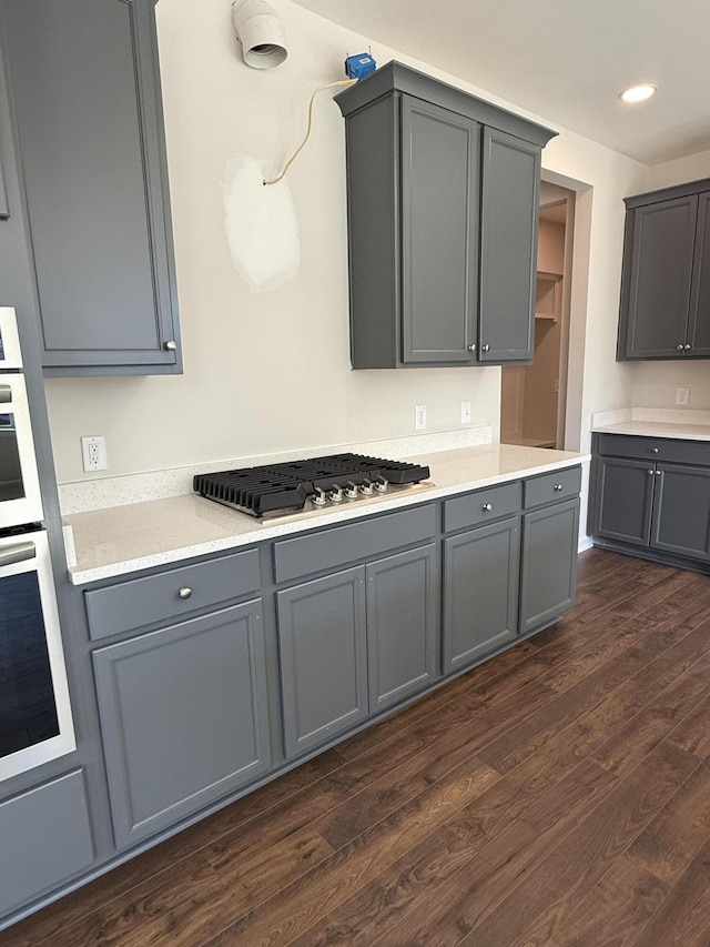 kitchen with appliances with stainless steel finishes, dark wood-style flooring, gray cabinets, and light countertops