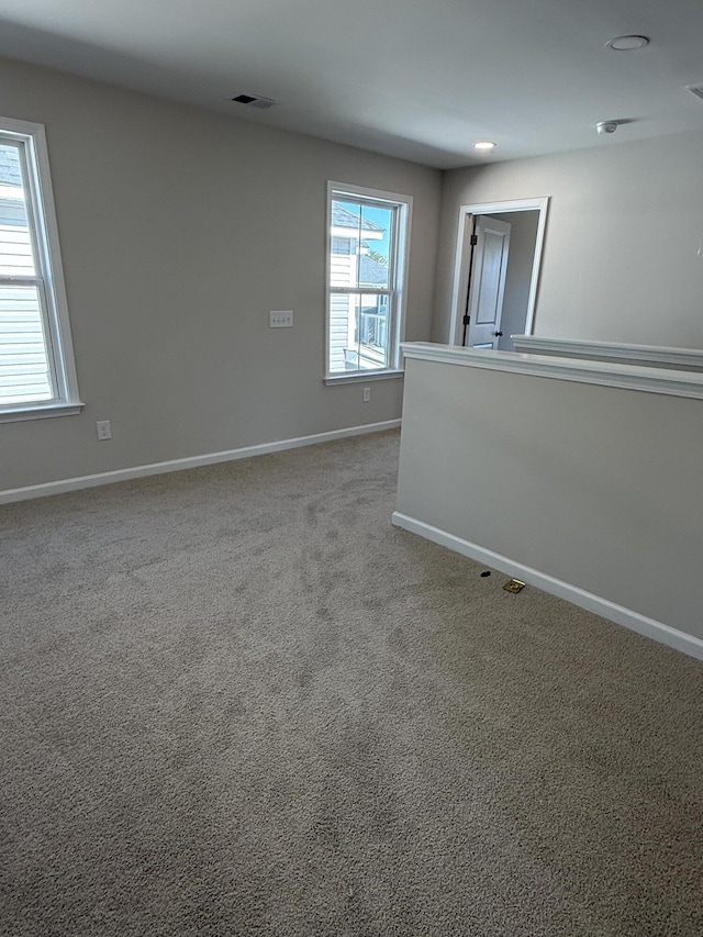 empty room featuring visible vents, baseboards, and carpet flooring