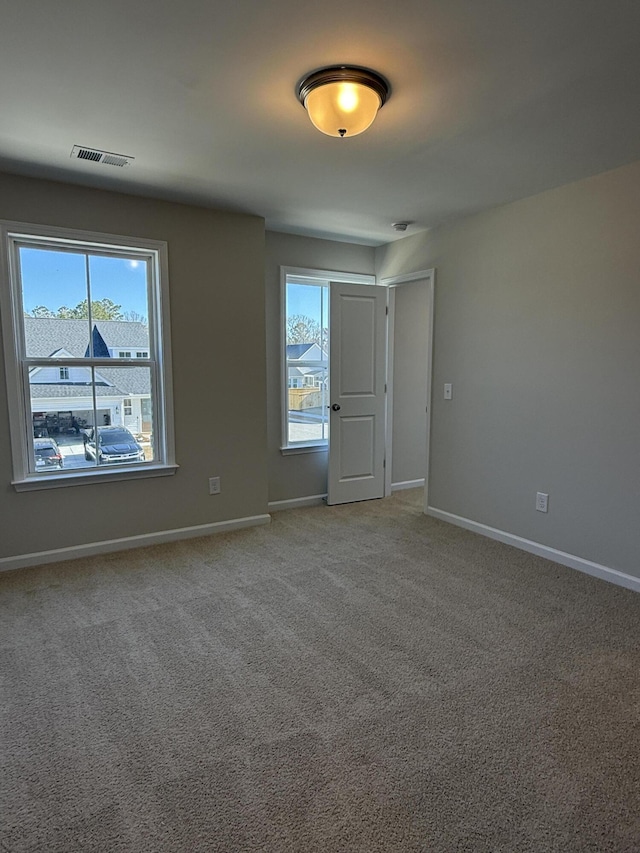 empty room with visible vents, light colored carpet, and baseboards