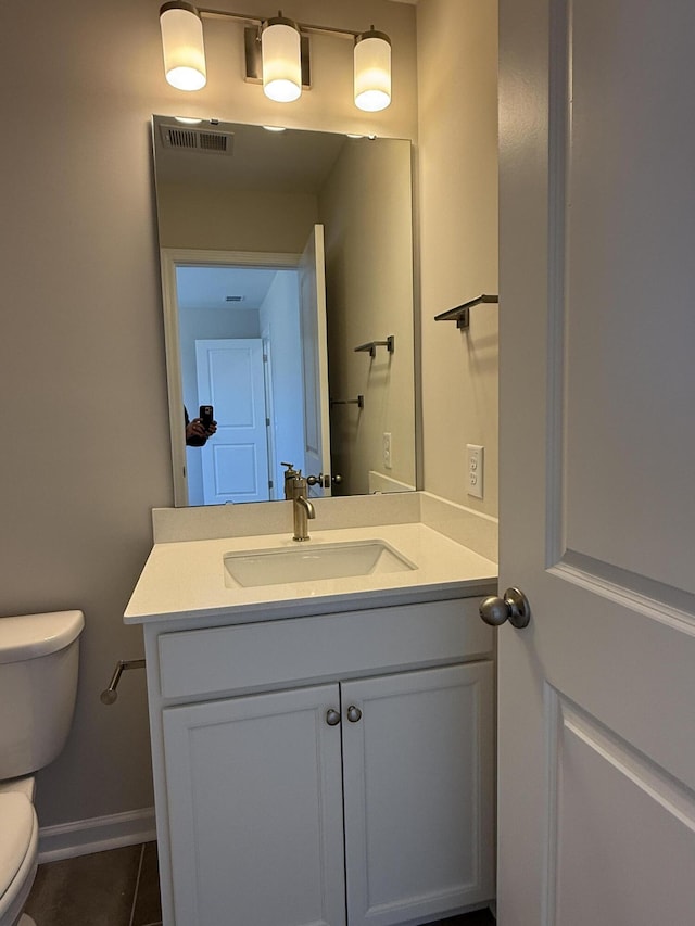 half bathroom with vanity, baseboards, visible vents, tile patterned floors, and toilet