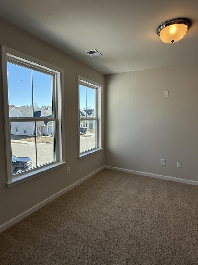 unfurnished room with visible vents, plenty of natural light, carpet, and baseboards