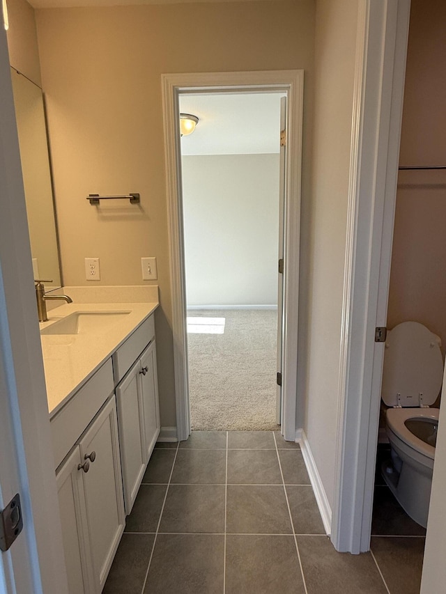 bathroom featuring tile patterned flooring, toilet, vanity, and baseboards